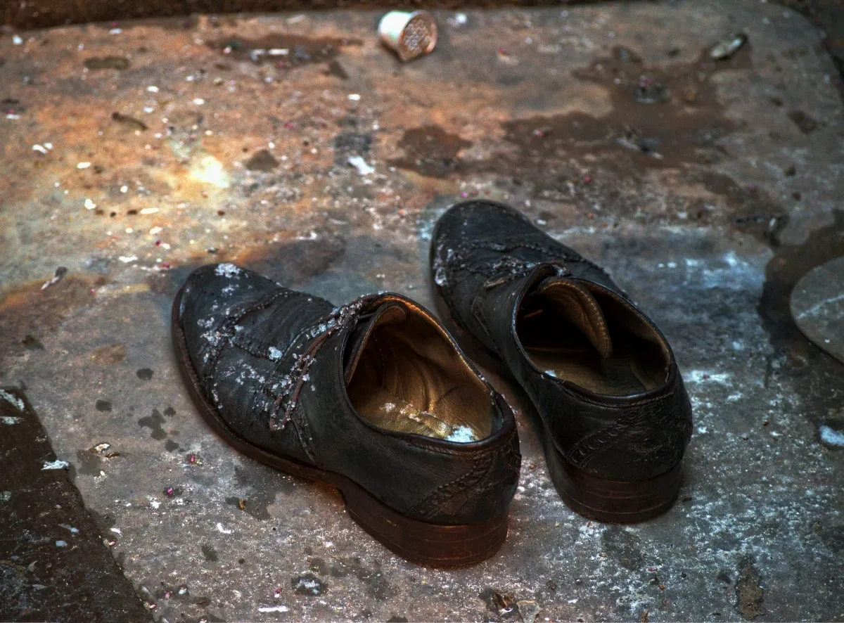 Pair of worn black shoes on a gritty, stained floor